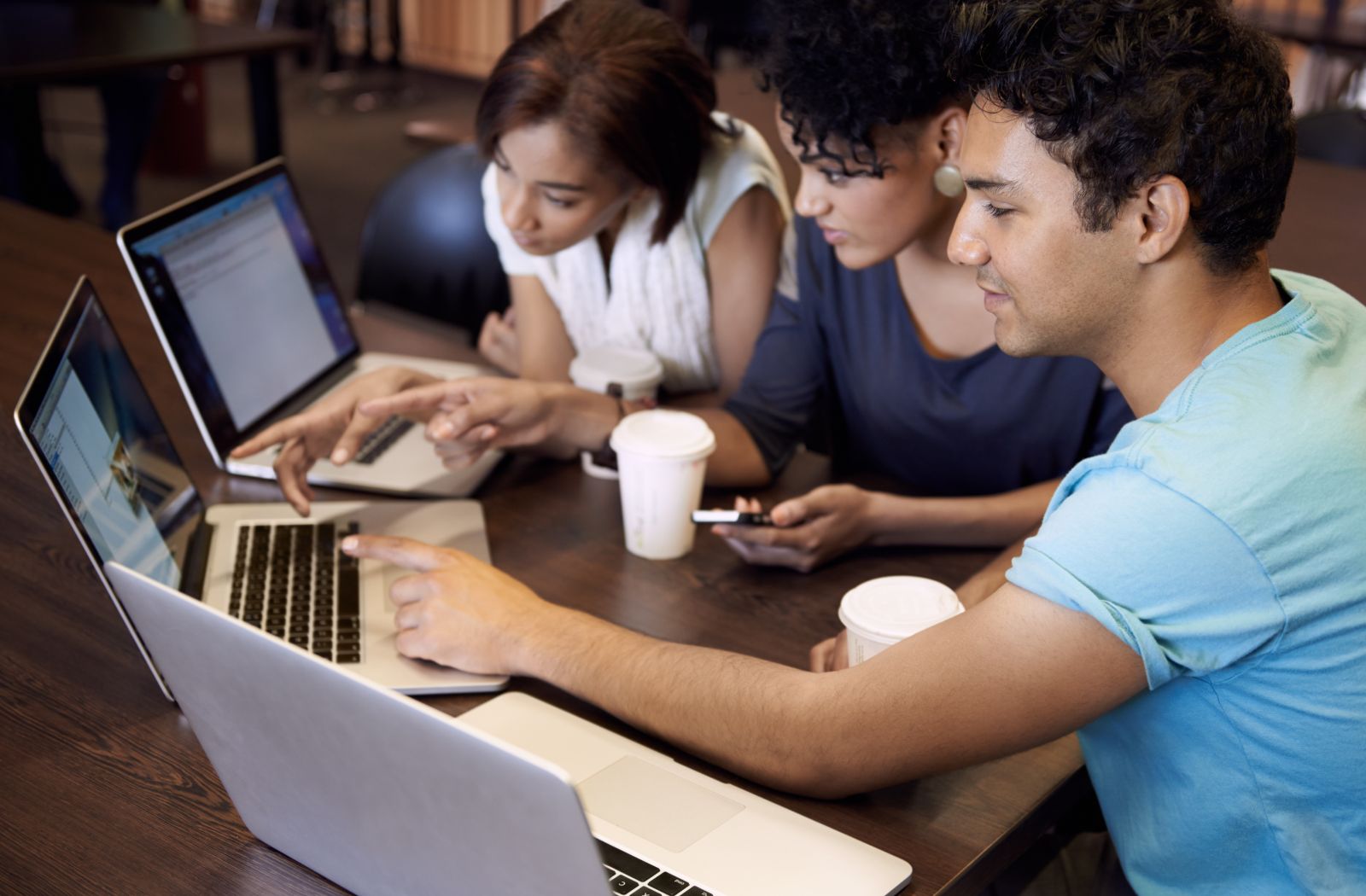 three young people around laptops