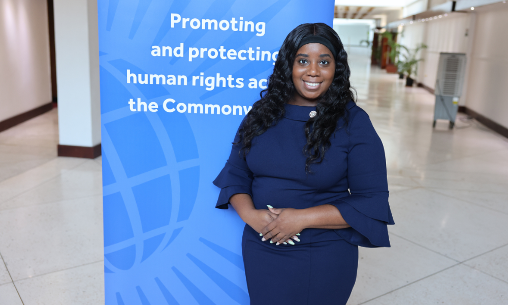 Rachel Lee, a workshop participant, stands in front of a Commonwealth Human Rights Unit sign