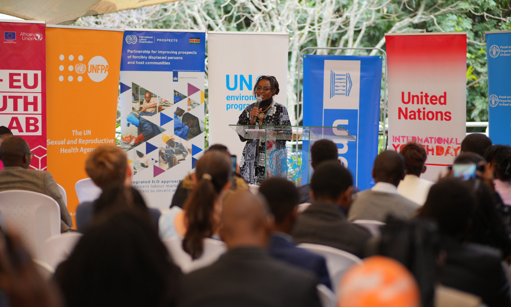 A woman speaks at the podium in front of an audience