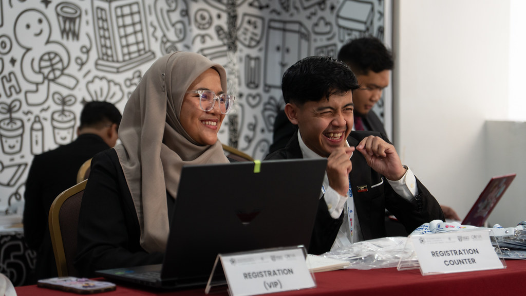 Two people from Malaysia sit next to each other smiling