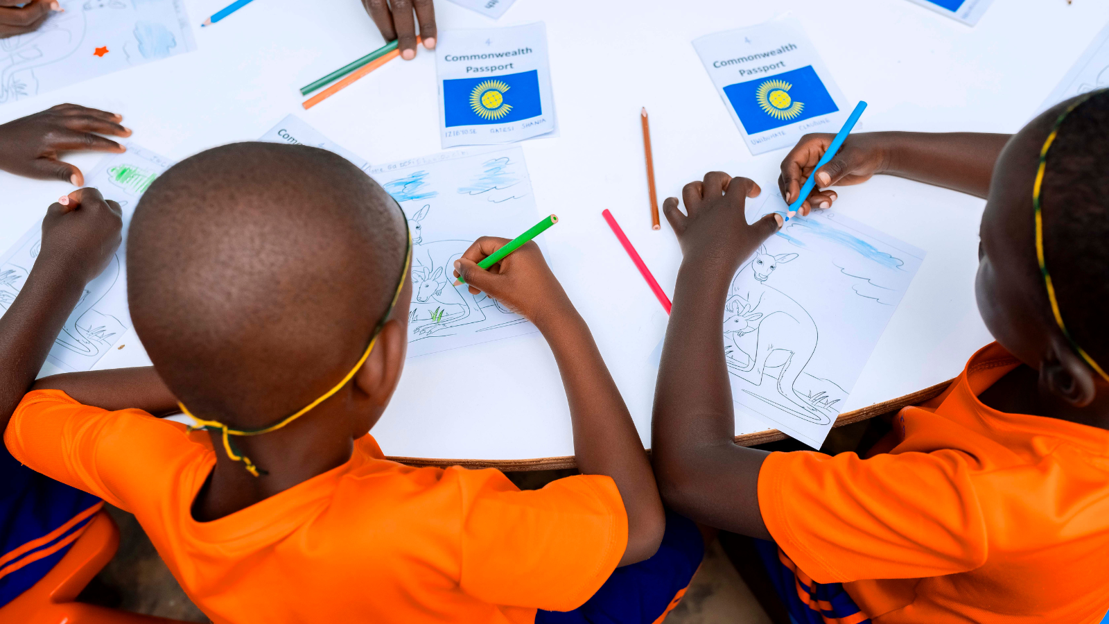 Two children colour in a kangaroo colouring sheet with a Commonwealth passport in the background
