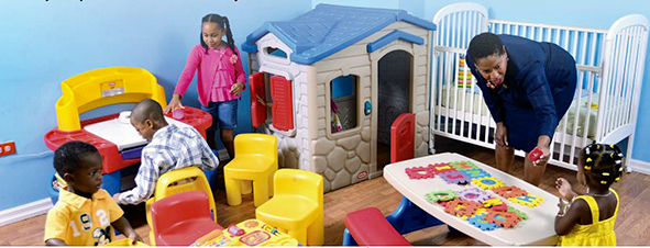 four young children play with a variety of toys in a dedicated playroom or play area, under the care of a professionally dressed woman