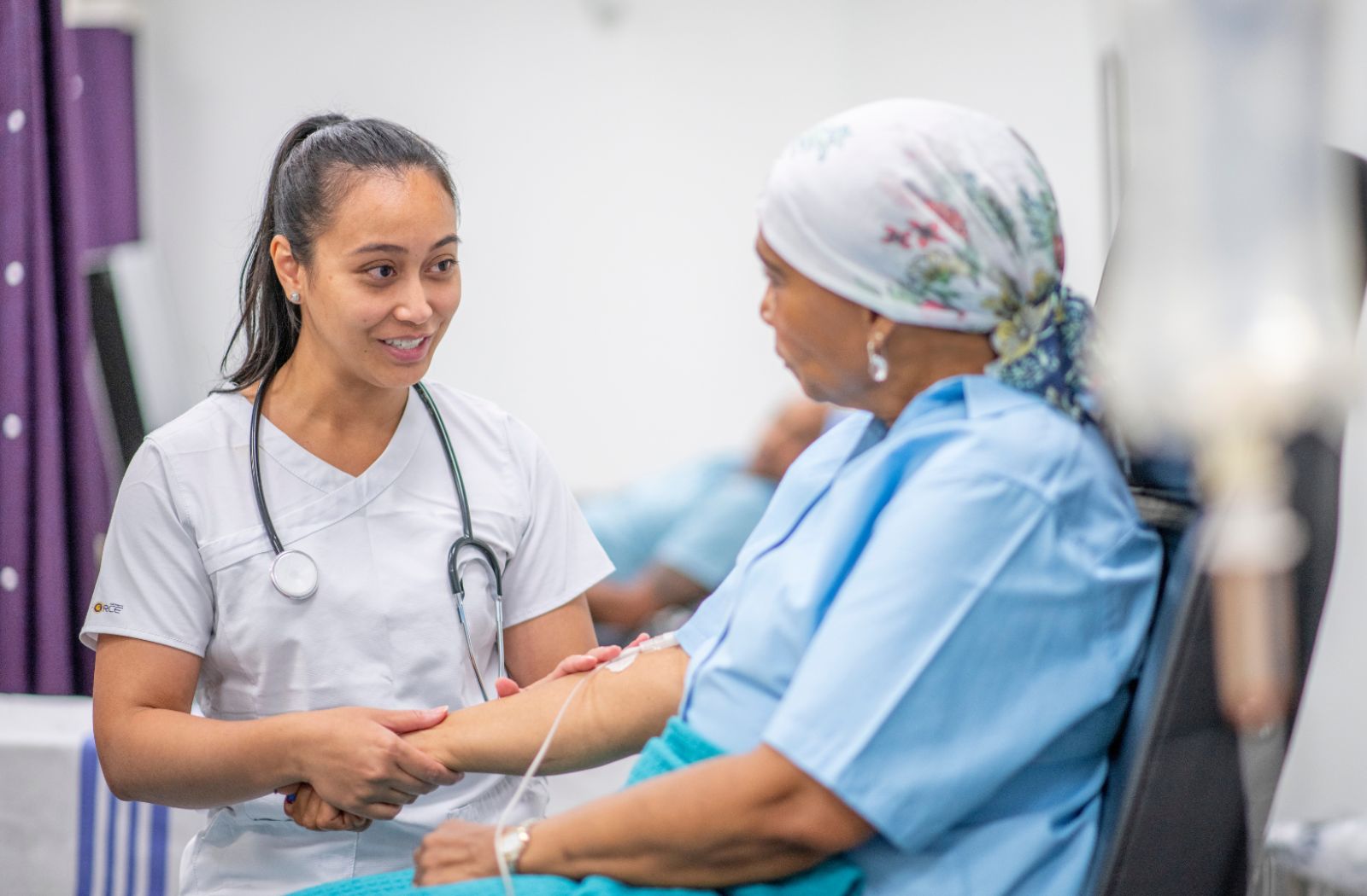 A female nurse speaks to a patient receiving cancer treatment
