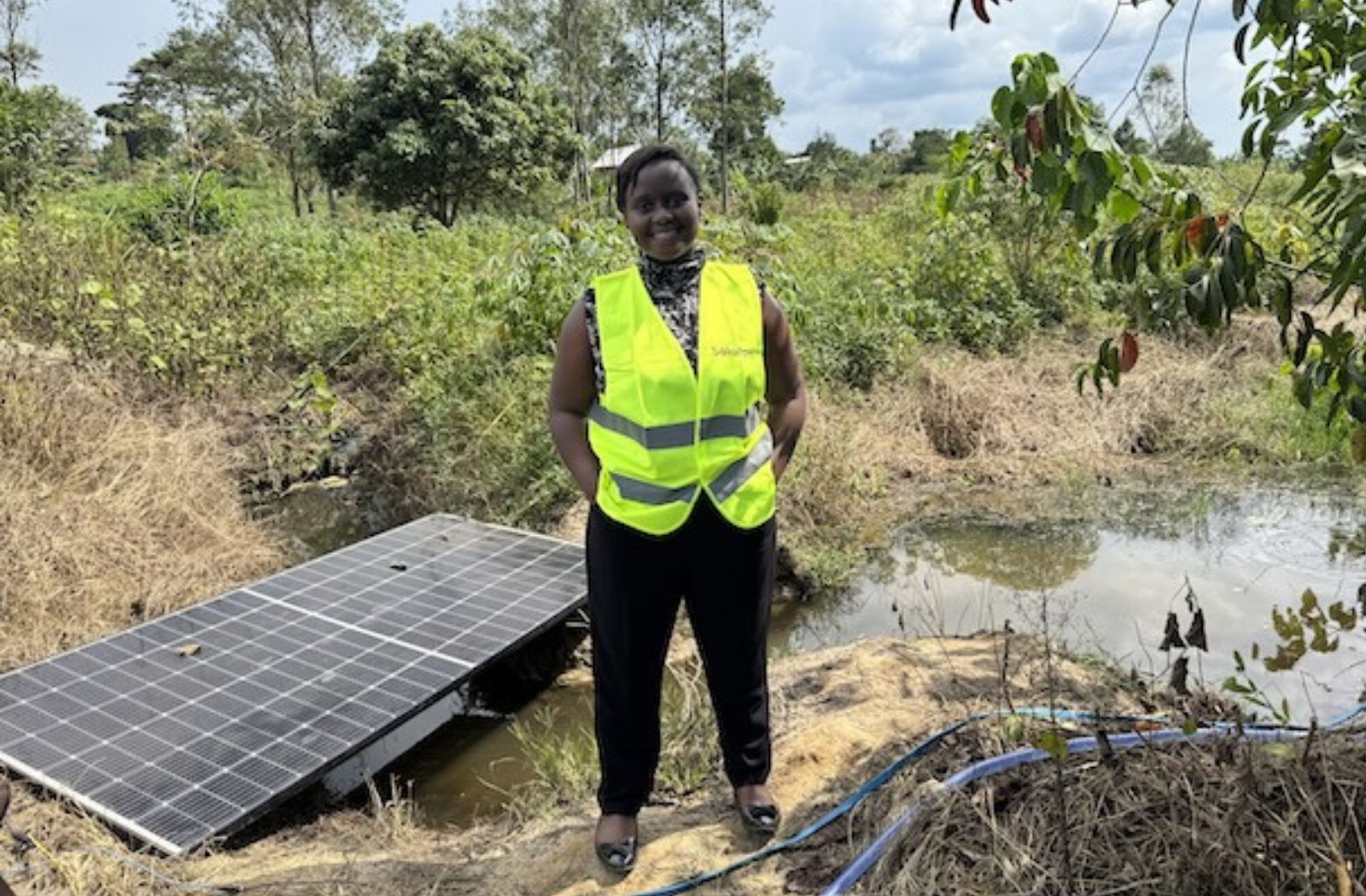 Shifra Ainomugisha poses beside a solar-powered irrigation system in Uganda