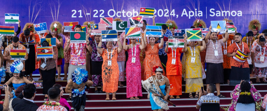 Young people hold up Commonwealth country flags at the Commonwealth Youth Forum at CHOGM 2024 in Samoa