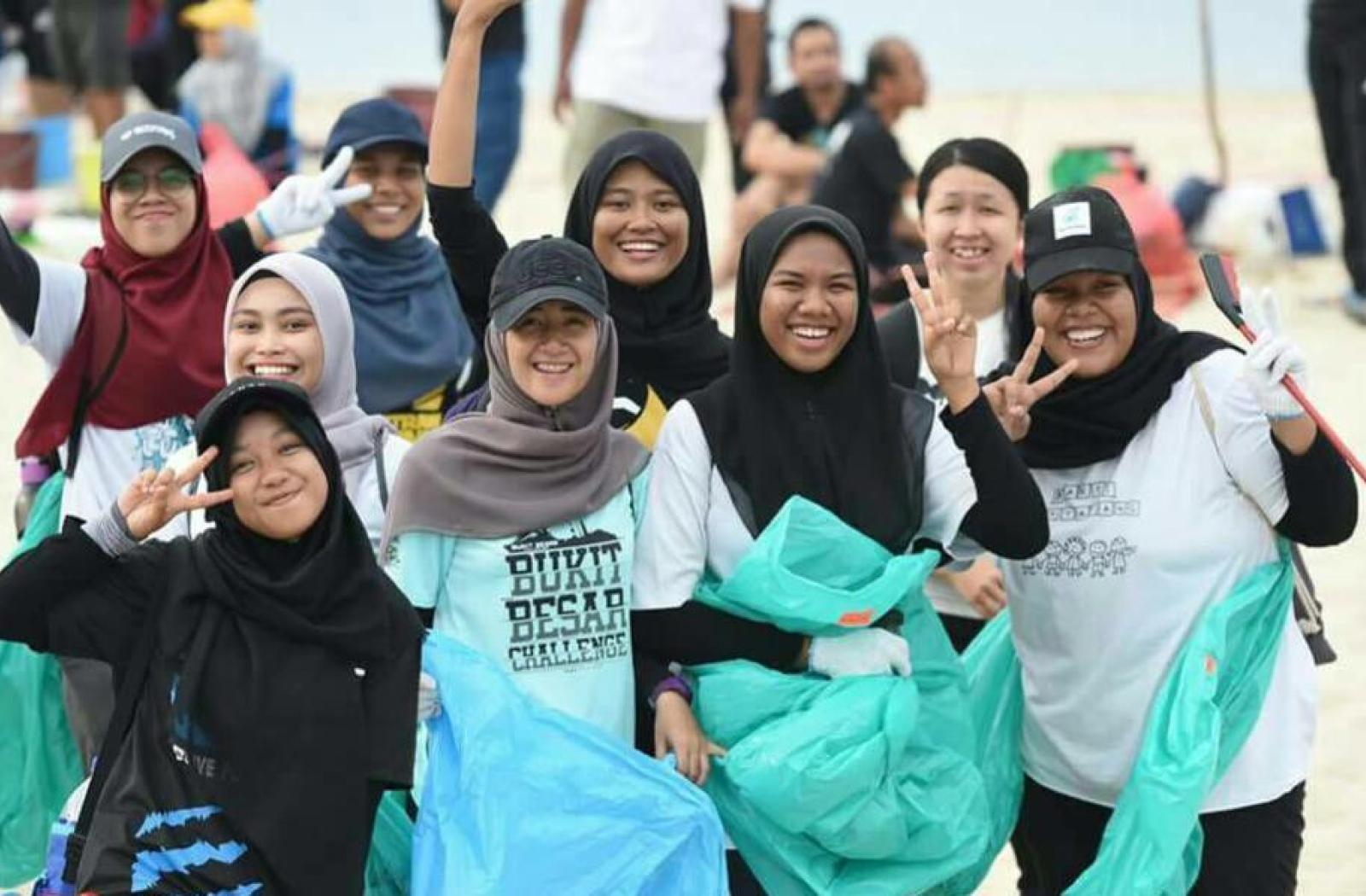 Youth in Malaysia picking up litter on a beach