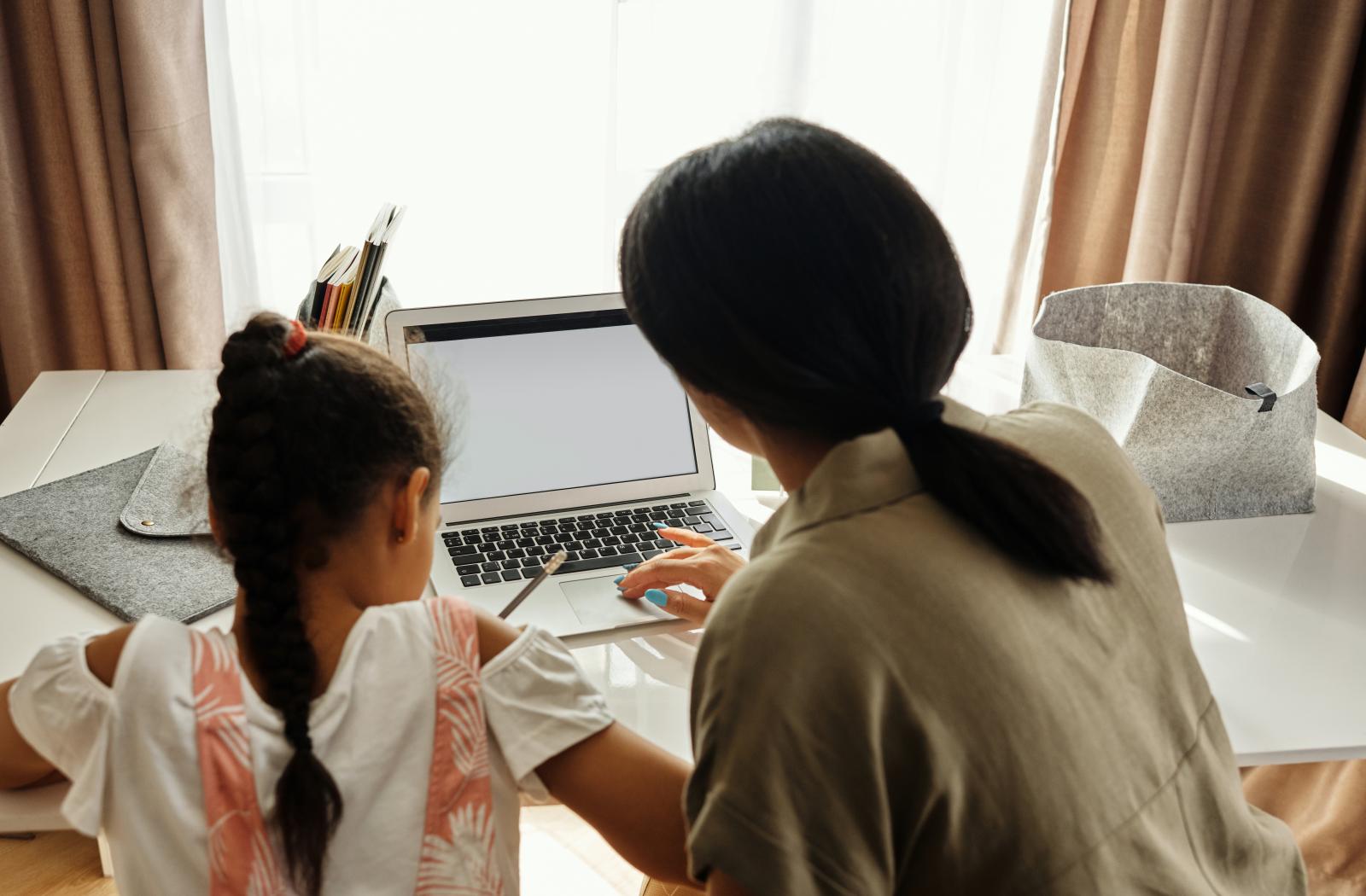 A woman and her daughter work on a laptop