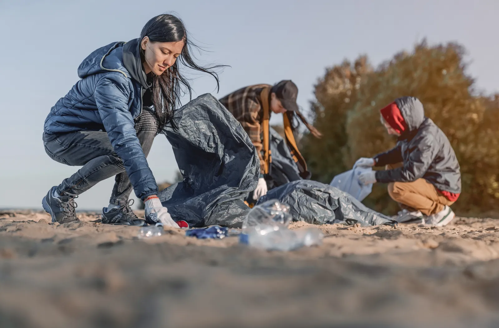 A group of young people picking up litter on a beach