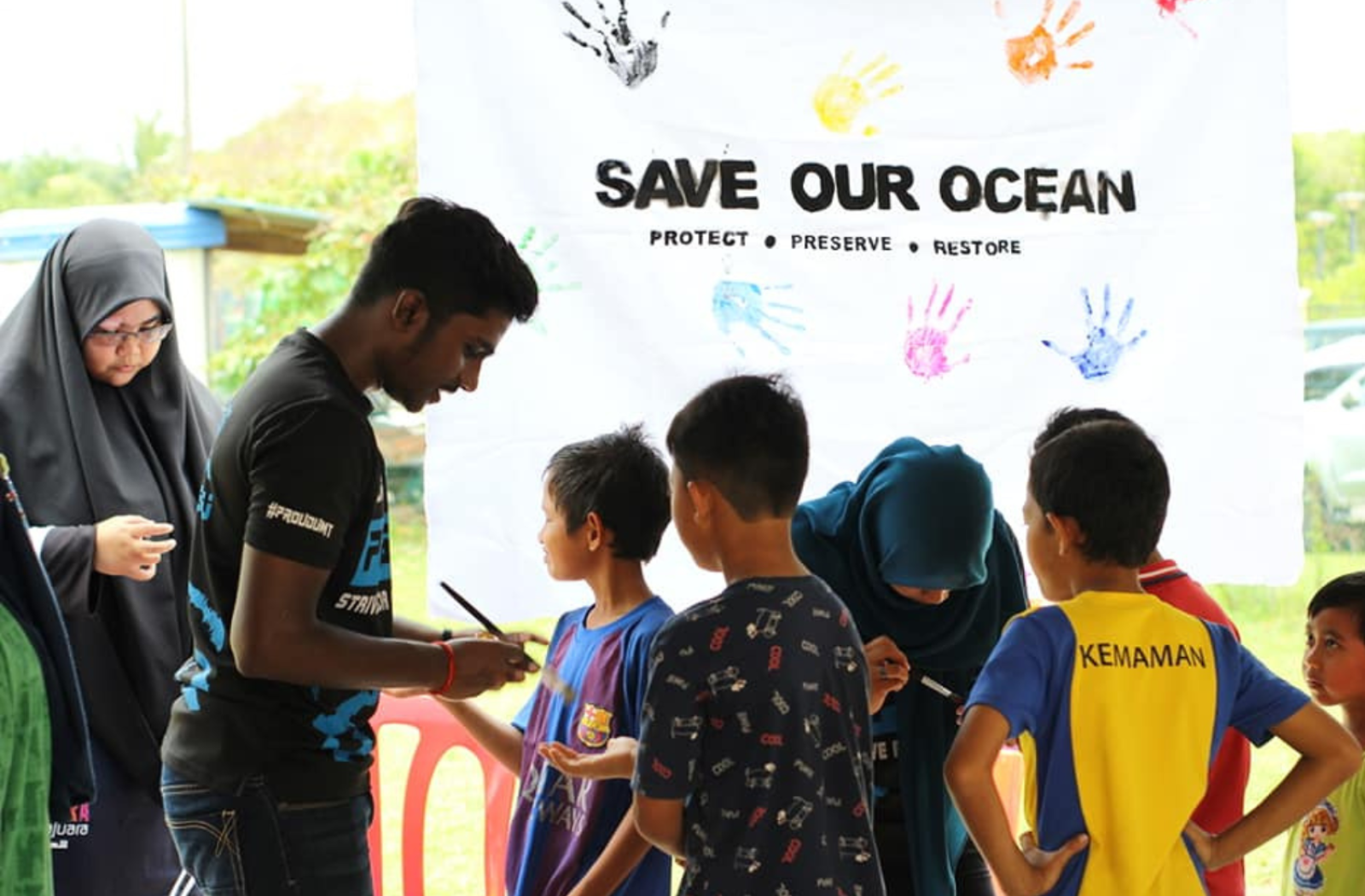 A group of young people in front of a sign that says "Save our Ocean"