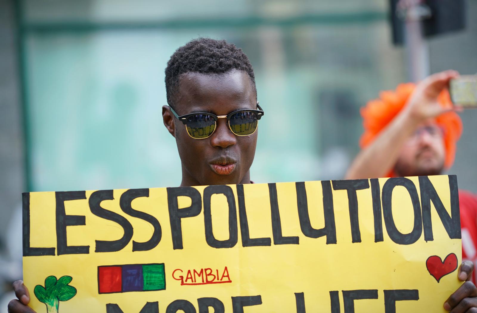 A man holding a sign saying 'Less pollution'