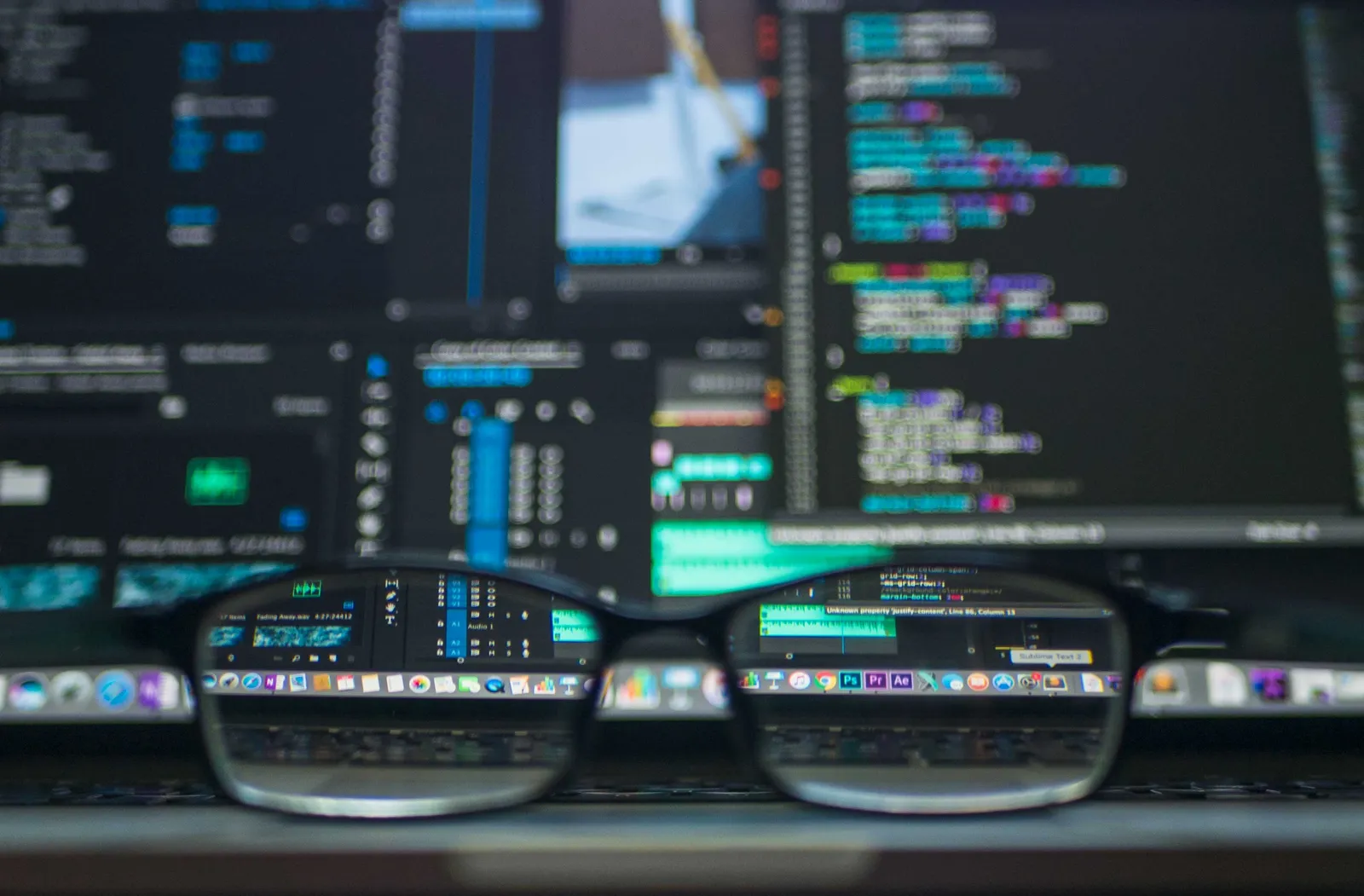 reading glasses in front of monitors displaying financial data