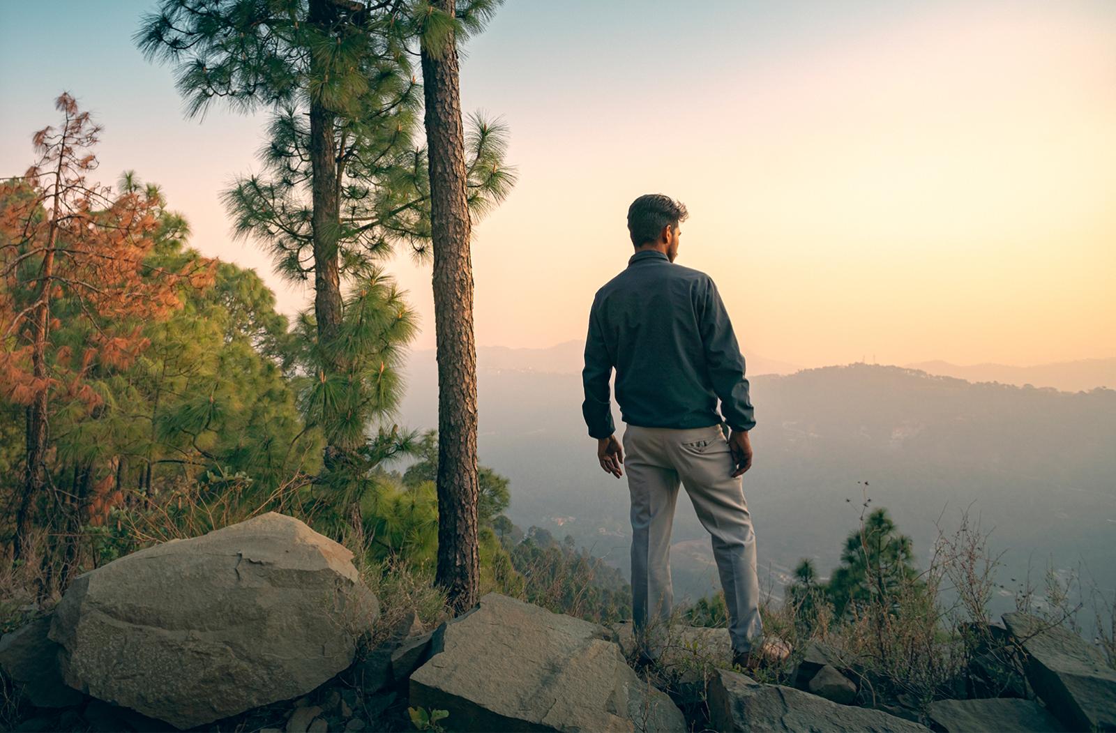 young man surveys a forested hillscape
