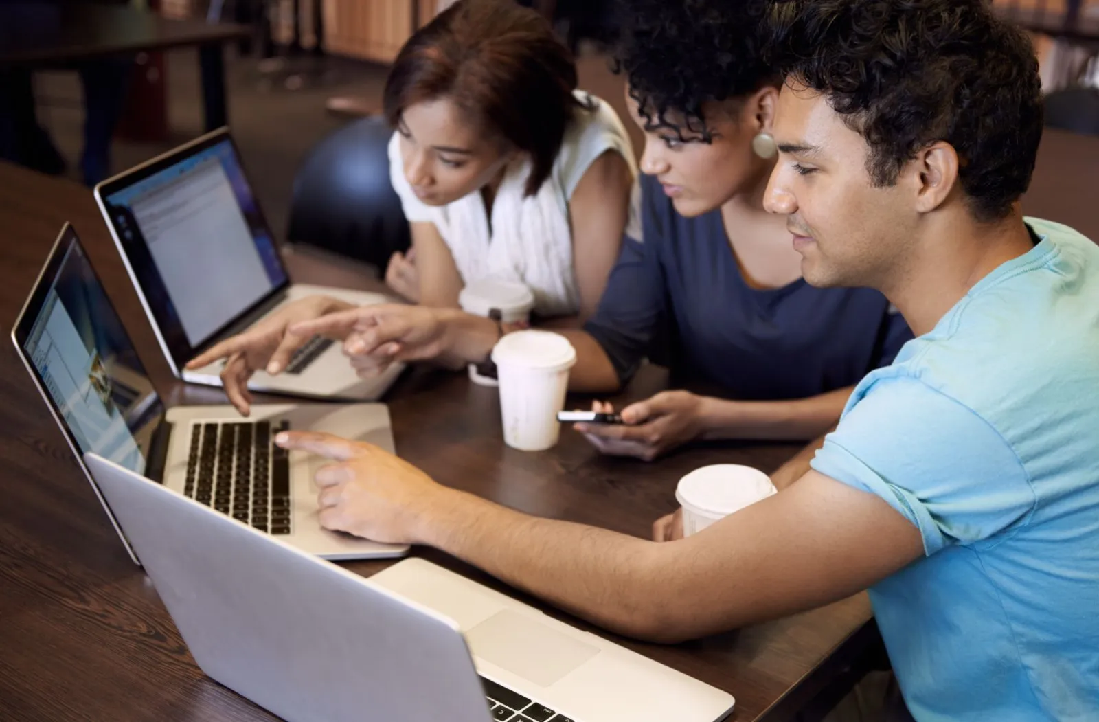 three young people around laptops