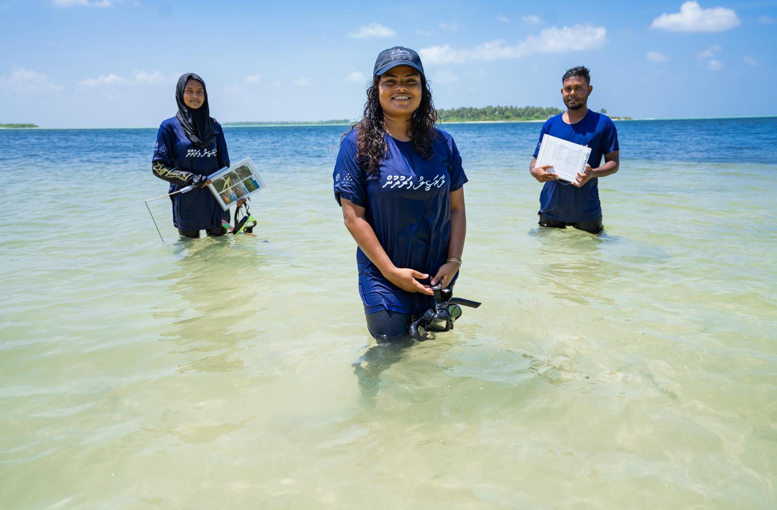 Three people standing in water with research equipment