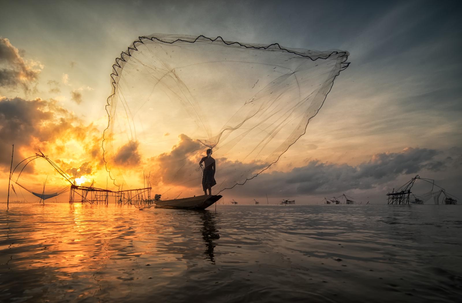 Fisherman on a boat throwing traditional net