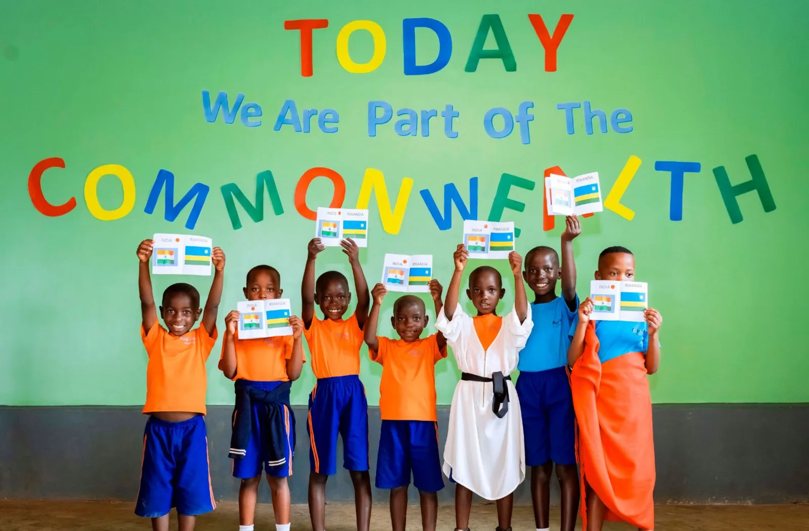 A group photo of children at Aspire Academy in front of a sign that says 'Today we are part of the Commonwealth'