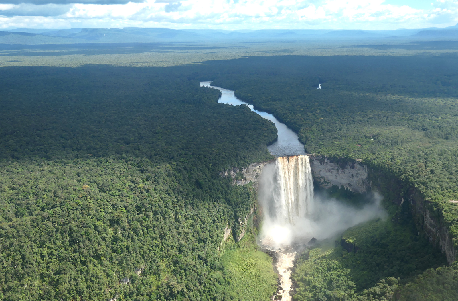 An aerial view of a waterfall in Guyana surrounded by forest