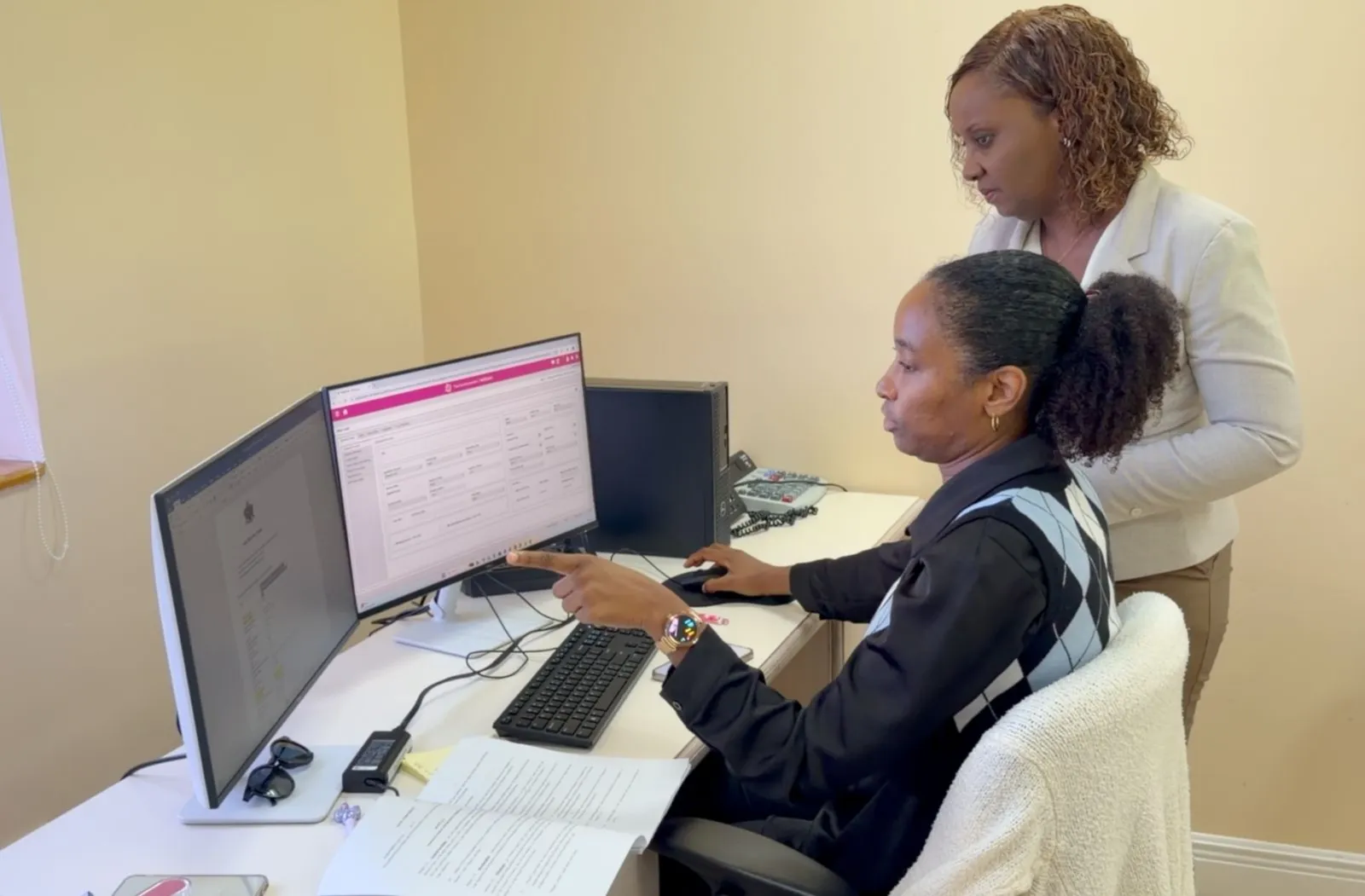 Two officials in Saint Lucia's Ministry of Finance look at the Commonwealth Meridian system on two computer screens