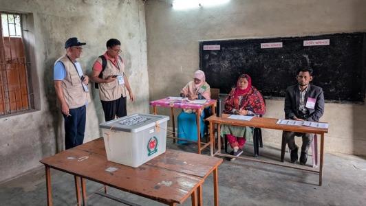 Two Commonwealth observers observe voting at a polling station in Bangladesh