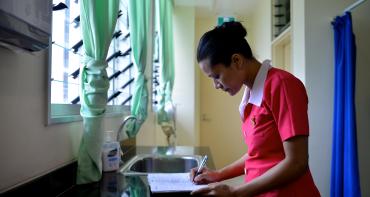 A nurse writes in a notebook at a hospital in Tonga