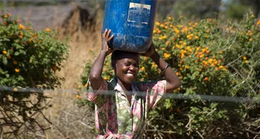 A woman carrying a bucket of water on her head (Credit: Jeff Walker/CIFOR)