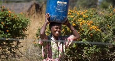 A woman carrying a bucket of water on her head (Credit: Jeff Walker/CIFOR)