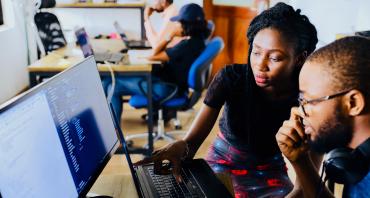 Two young people look at computer screen