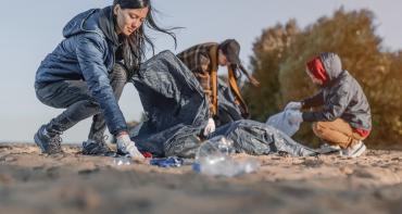 A group of young people picking up litter on a beach