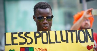 A man holding a sign saying 'Less pollution'