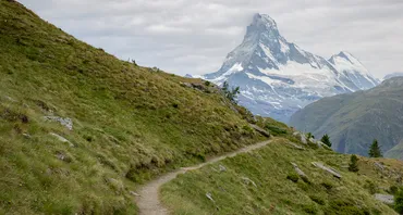 A photograph of a narrow hillside path leading to a tall mountain (the Matterhorn on the Italian-Swiss border)