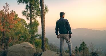 young man surveys a forested hillscape