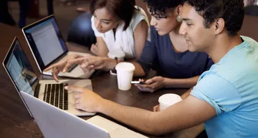 three young people around laptops