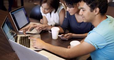 three young people around laptops