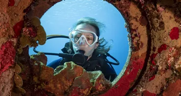 woman diver looking through coral