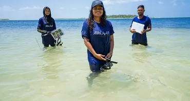 Three people standing in water with research equipment