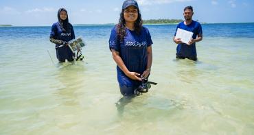 Three people standing in water with research equipment