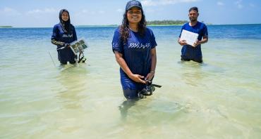 Three people standing in water with research equipment