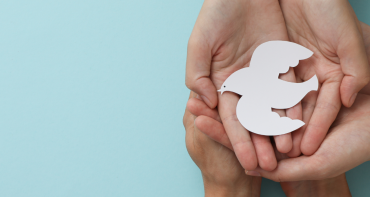 young people hold hands to represent a peace dove