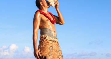 Man in Samoan traditional dress blowing conch shell at CHOGM joint forum opening ceremony
