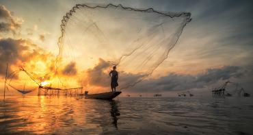 Fisherman on a boat throwing traditional net