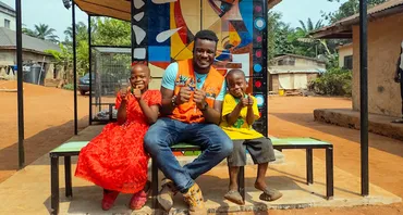 Stanley Anigbogu with a young girl and boy sitting by a solar charging station