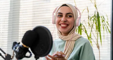 A woman in a hijab speaks into a microphone