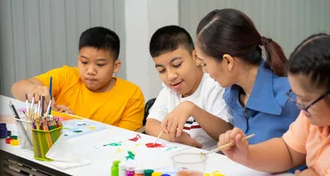 A teacher shows children how to paint