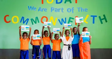 A group photo of children at Aspire Academy in front of a sign that says 'Today we are part of the Commonwealth'