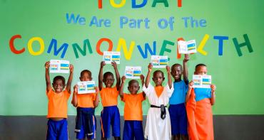 A group photo of children at Aspire Academy in front of a sign that says 'Today we are part of the Commonwealth'