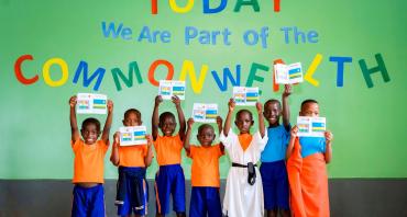 A group photo of children at Aspire Academy in front of a sign that says 'Today we are part of the Commonwealth'