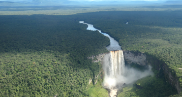 An aerial view of a waterfall in Guyana surrounded by forest