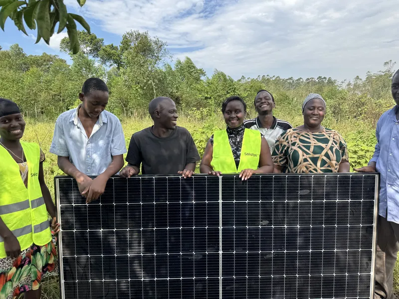 Commonwealth Youth Award Winner, Shifra Ainomugisha with farmers and community members beside a solar panel installation